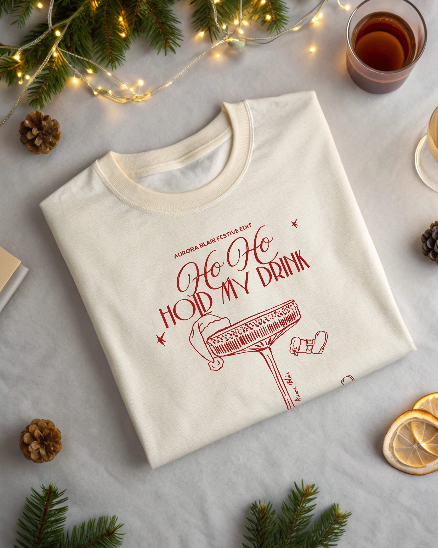 White sweatshirt with red text and graphics on a light surface with Christmas decorations.